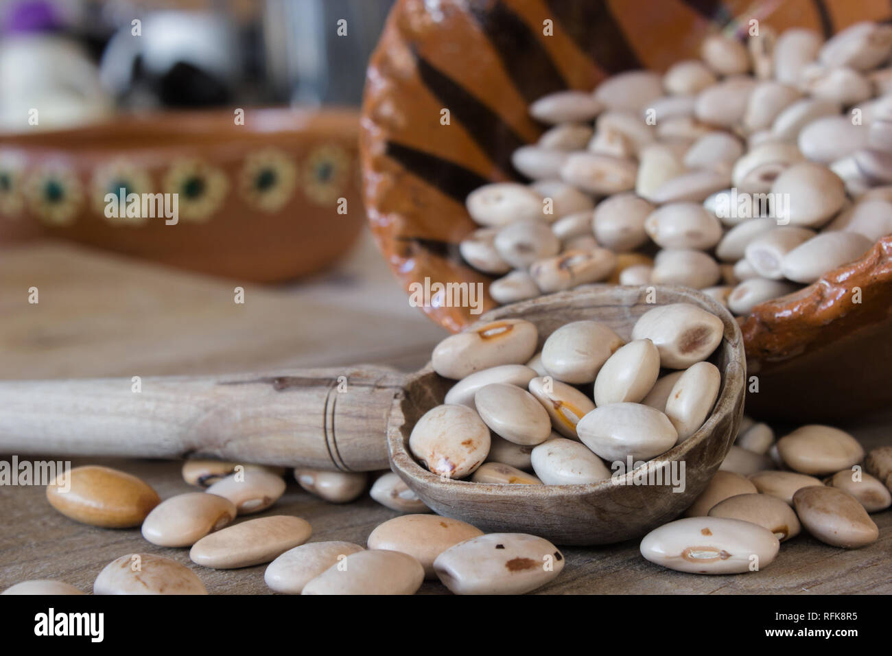 Fagiolo Bianco semi all'interno di un cucchiaio di legno, messicano artigianale di pentola di creta Foto Stock