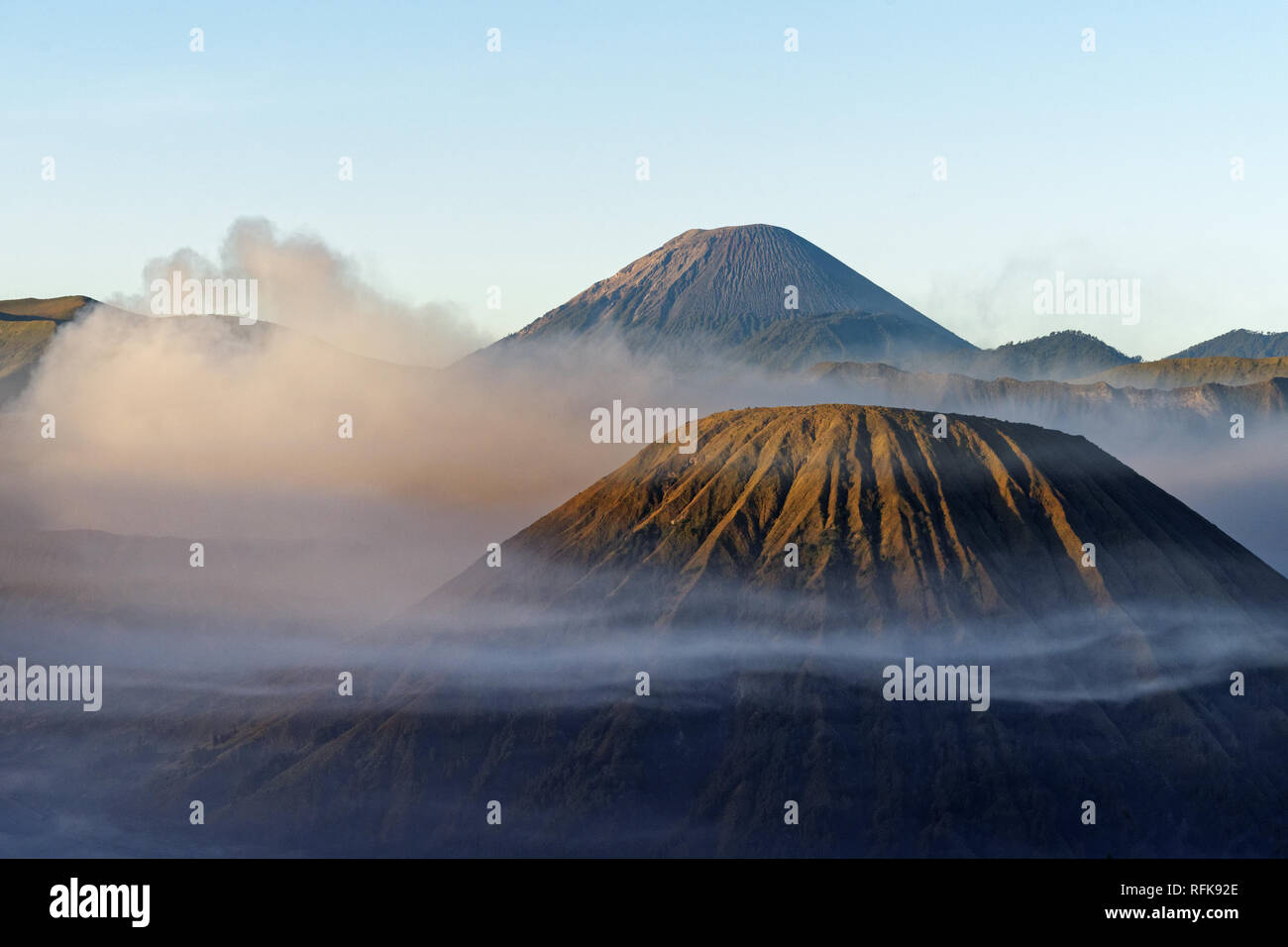 Vista nella luce del mattino su una montagna vulcanica circondata da nuvole e nebbia con fortemente strutturato fianchi - Posizione: Indonesia, Java, Mt. Bromo Foto Stock