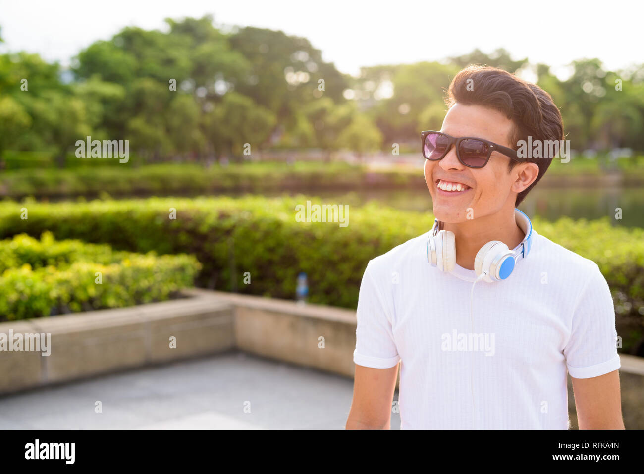 Giovane uomo asiatico che indossano le cuffie durante i momenti di relax presso il parco Foto Stock