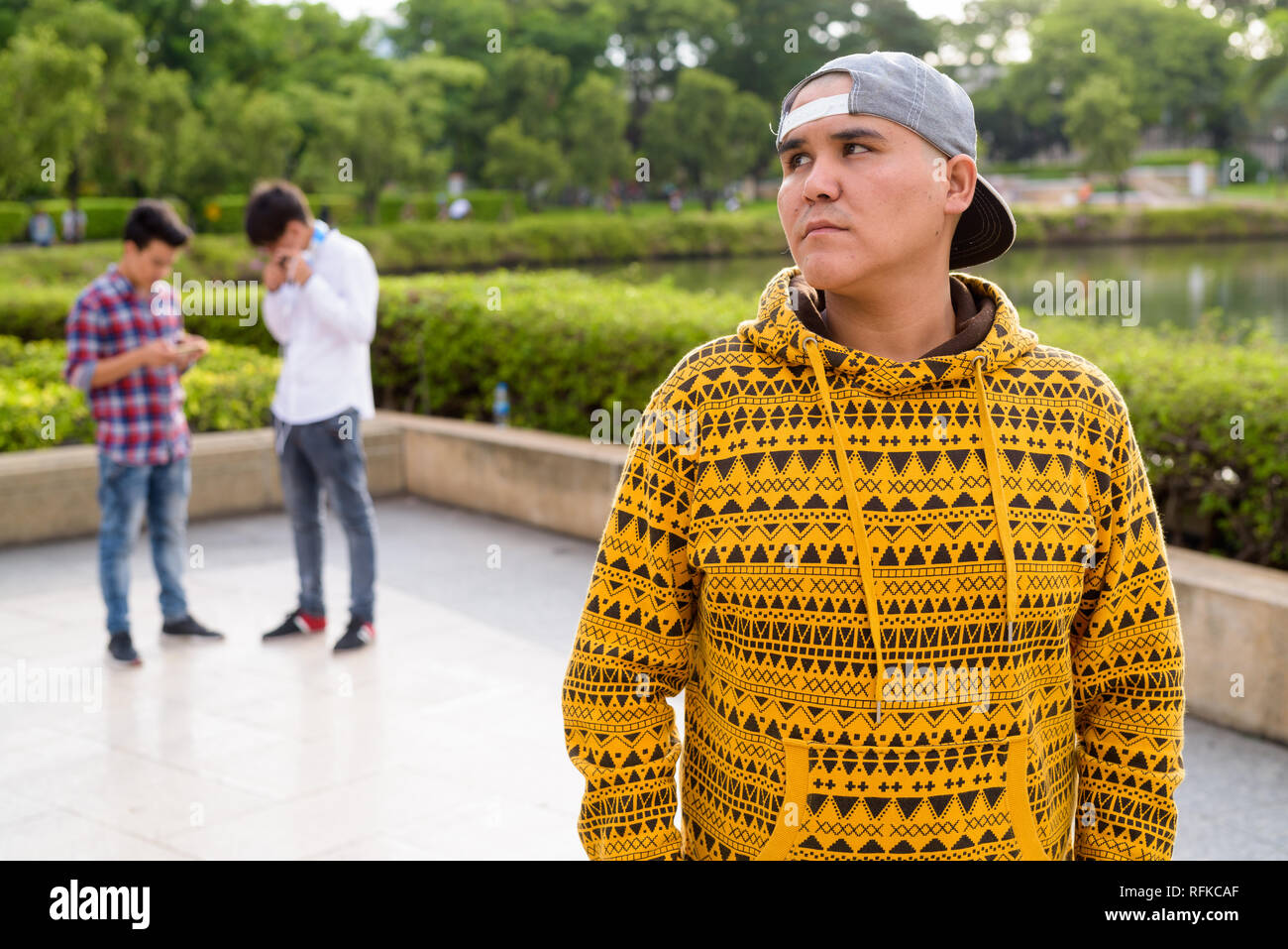 Tre giovani uomini asiatici di relax presso il parco insieme Foto Stock