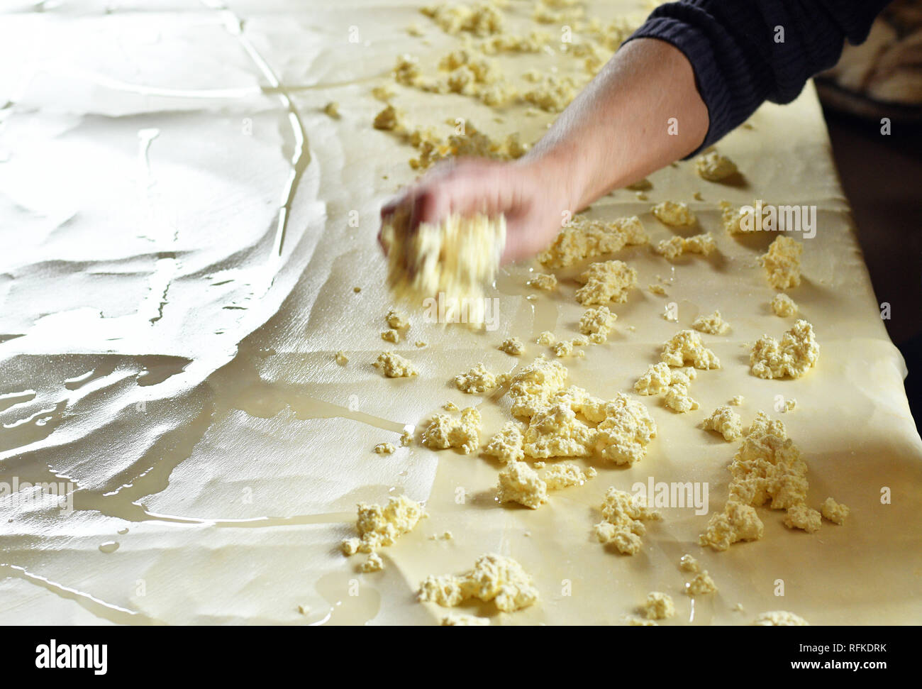 La pasta per lo strudel, distesa su un tavolo da cucina e aggiunta di formaggio su esso Foto Stock