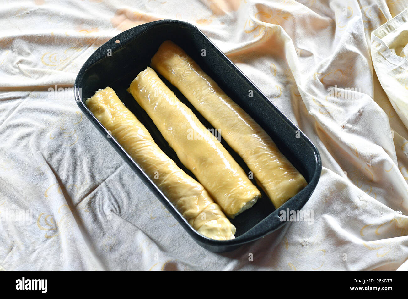 Impasto arrotolato per lo strudel con ricotta in esso in una teglia Foto Stock