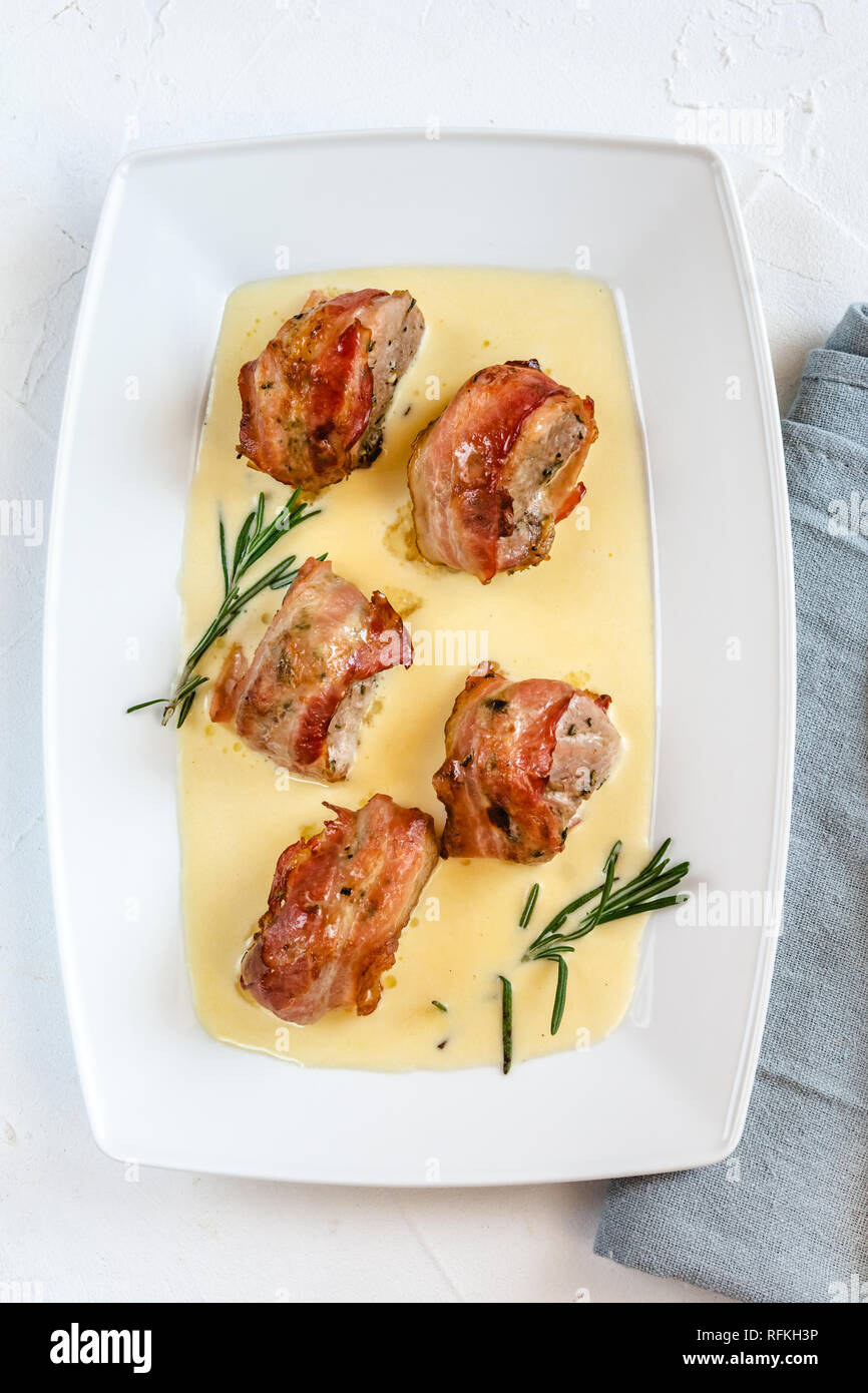 Cotto al forno filetto di maiale avvolto in pancetta e servito in una salsa  al formaggio con rosmarino Foto stock - Alamy