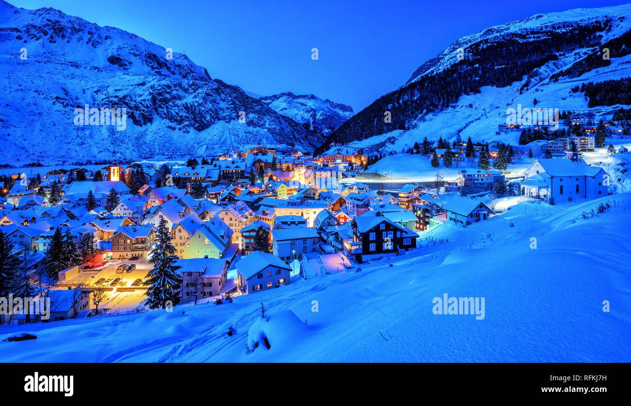 Andermatt villaggio nelle Alpi svizzere montagne coperte di neve in inverno in blu luce della sera, Vista panoramica, Uri, Svizzera Foto Stock
