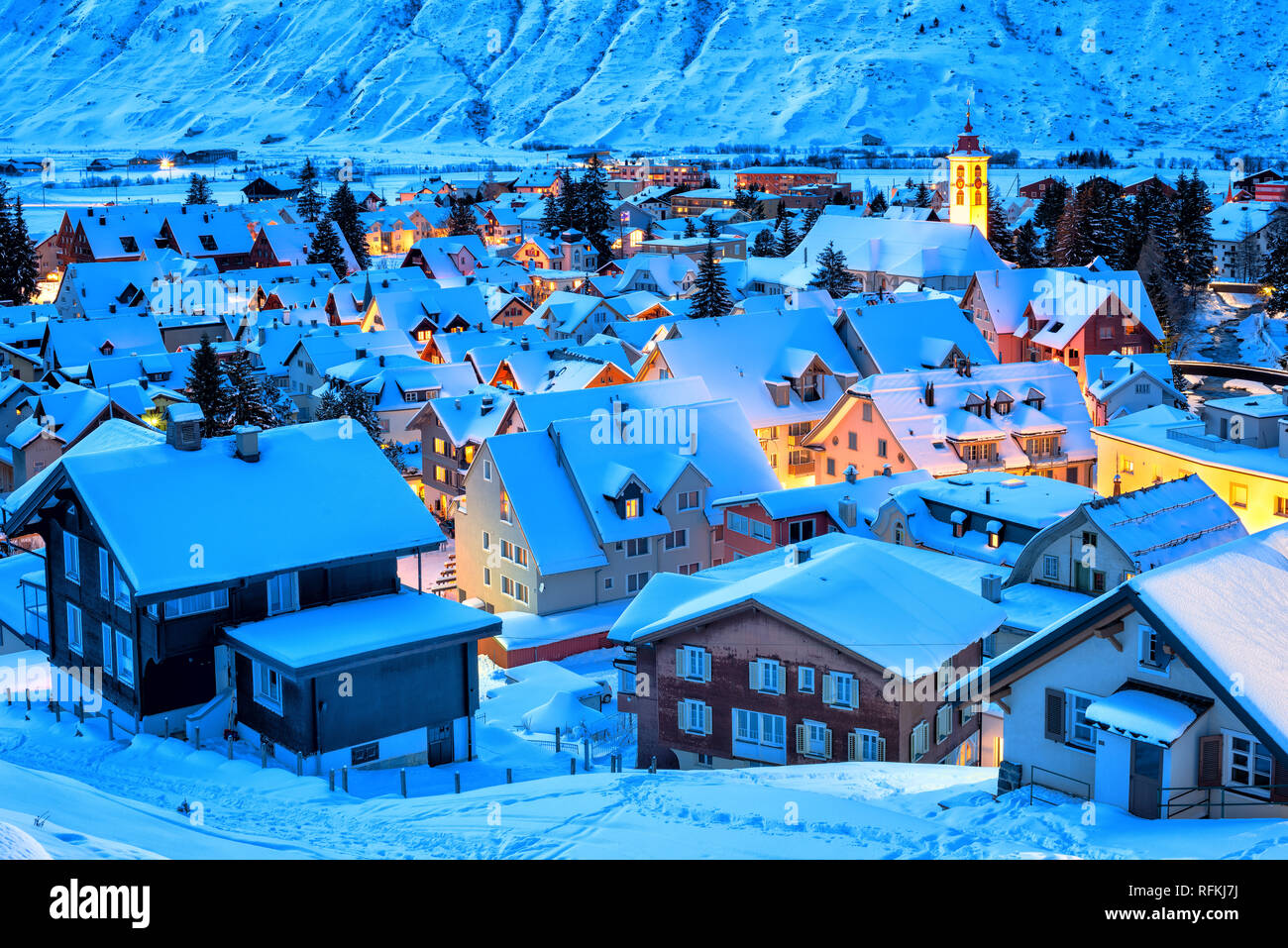 Andermatt villaggio nelle Alpi svizzere montagne coperte di neve in inverno in blu luce della sera, Uri, Svizzera Foto Stock