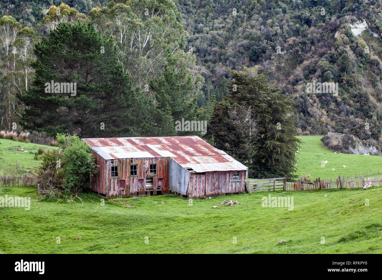 Un vecchio tosatura delle pecore capannone o fienile si trova accoccolato ai piedi della montagna nel verde del paesaggio. Foto Stock