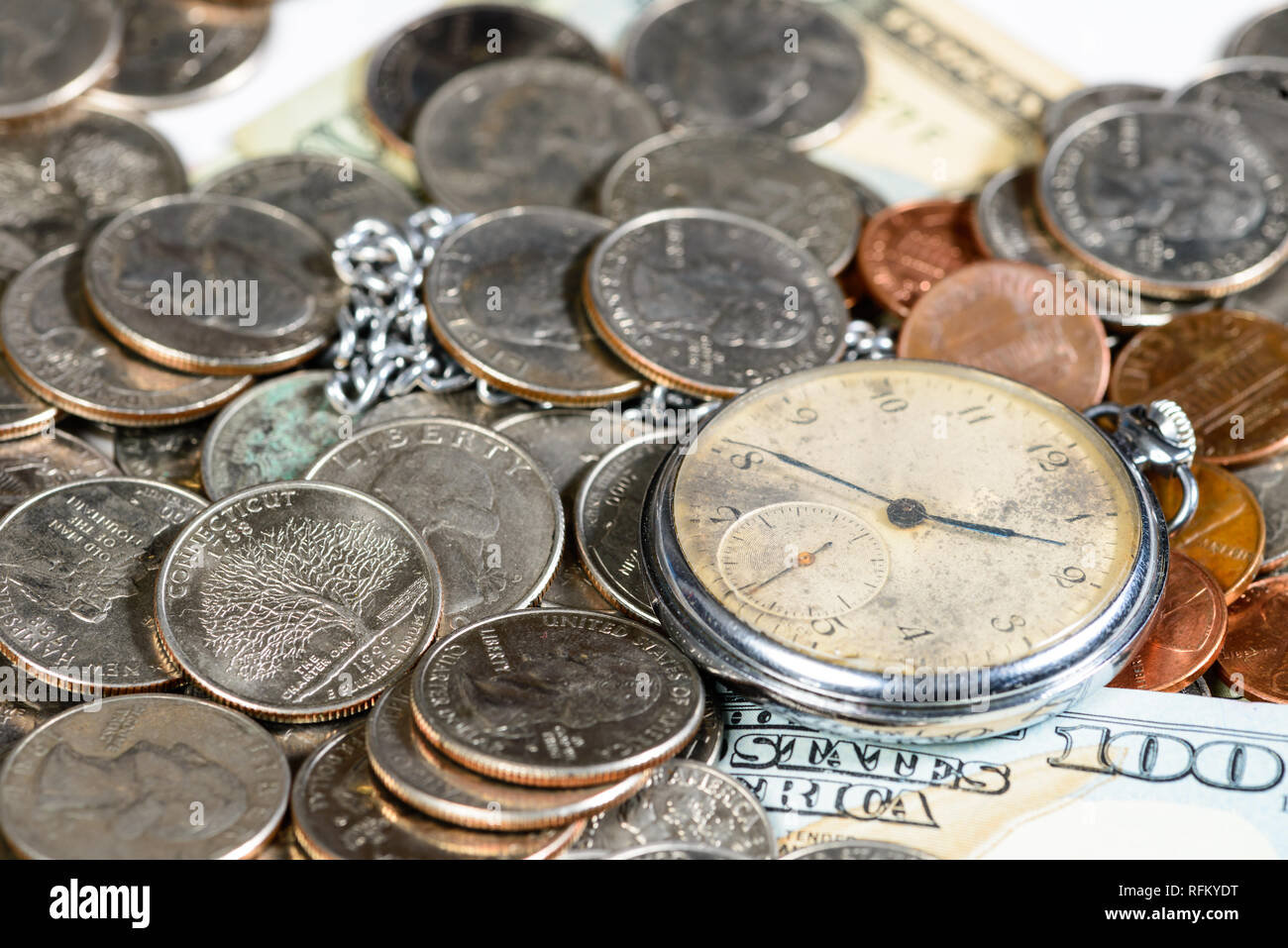 Tempo e denaro concetto Close up di un denaro e un vecchio orologio da tasca Foto Stock