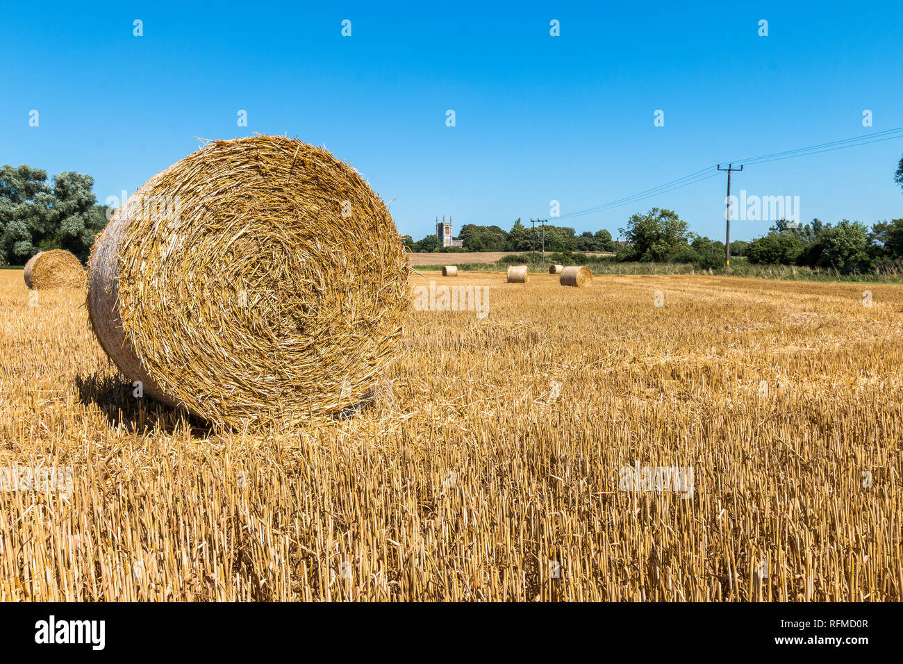 Round balle di fieno in un campo vicino alla chiesa di Tutti i Santi, Aldwincle, Northamptonshire Foto Stock