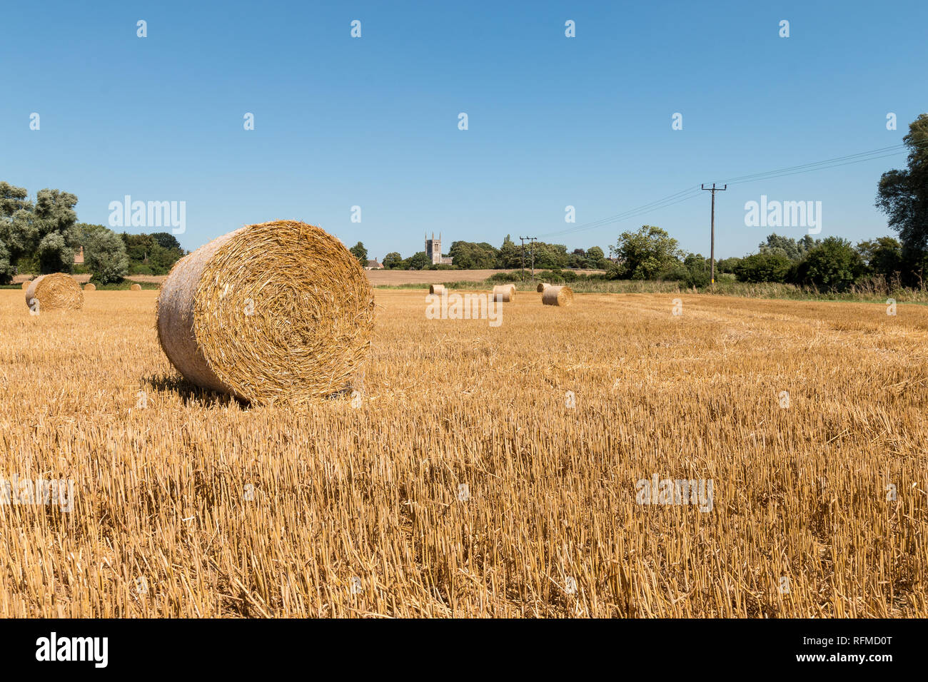 Round balle di fieno in un campo vicino alla chiesa di Tutti i Santi, Aldwincle, Northamptonshire Foto Stock