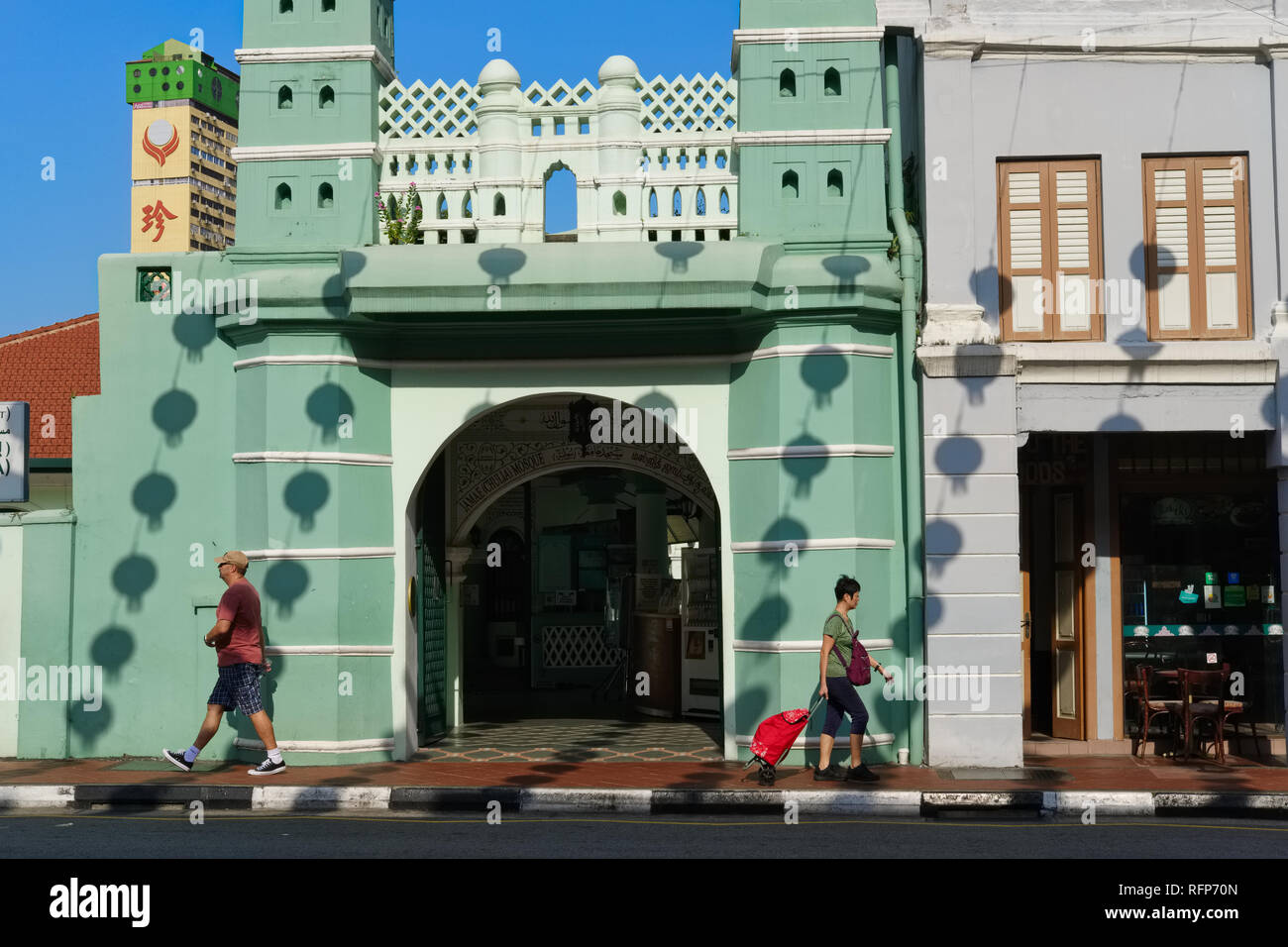 Persone di passaggio Moschea Jamae in Chinatown, Singapore, le ombre delle lanterne cinesi appesa sopra la strada si vede sulla parete della moschea Foto Stock