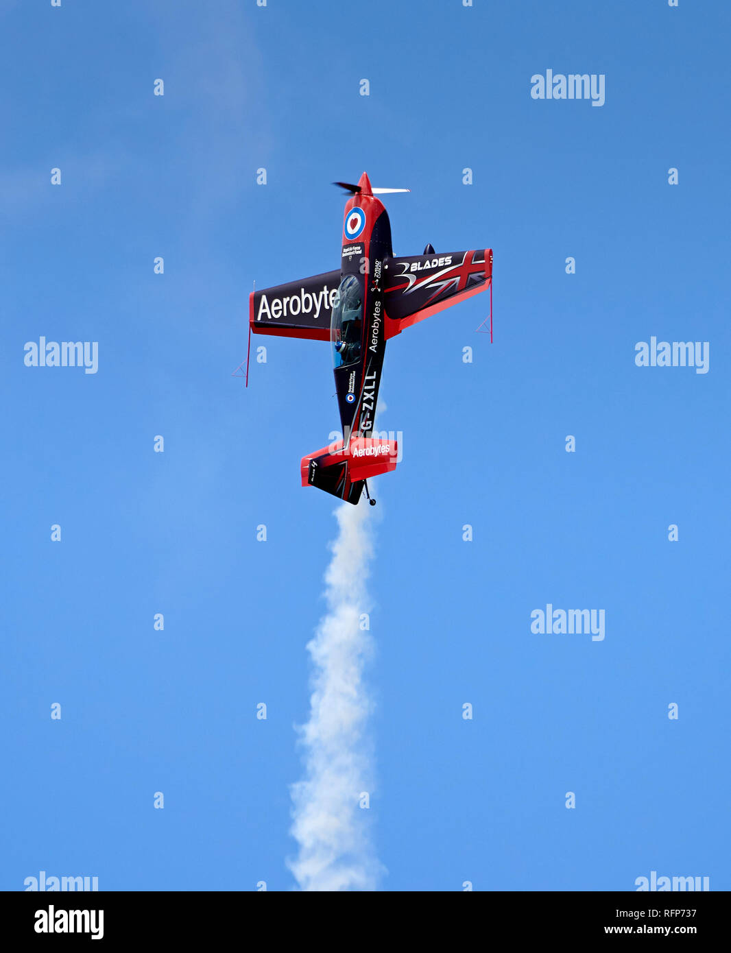 Una delle lame il display del Team Extra 300LS (finale del fumo bianco) si arrampica verticalmente in un cielo blu. Foto Stock