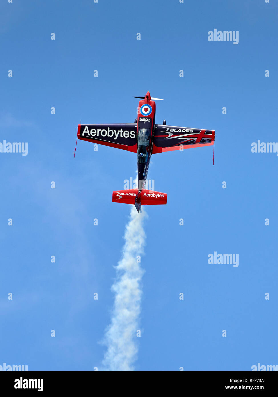Una delle lame il display del Team Extra 300LS (finale del fumo bianco) si arrampica verticalmente in un cielo blu. Foto Stock