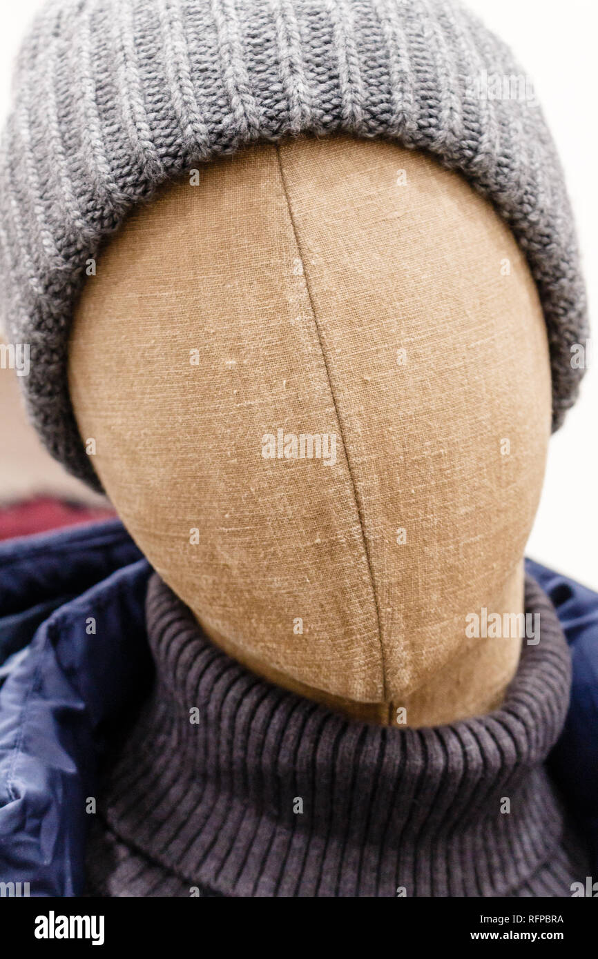 Ritratto di manichino testa realizzata in tessuto marrone con lana grigio cappello, maglione scuro e blu scuro giacca nel negozio di moda showroom per gli uomini Foto Stock