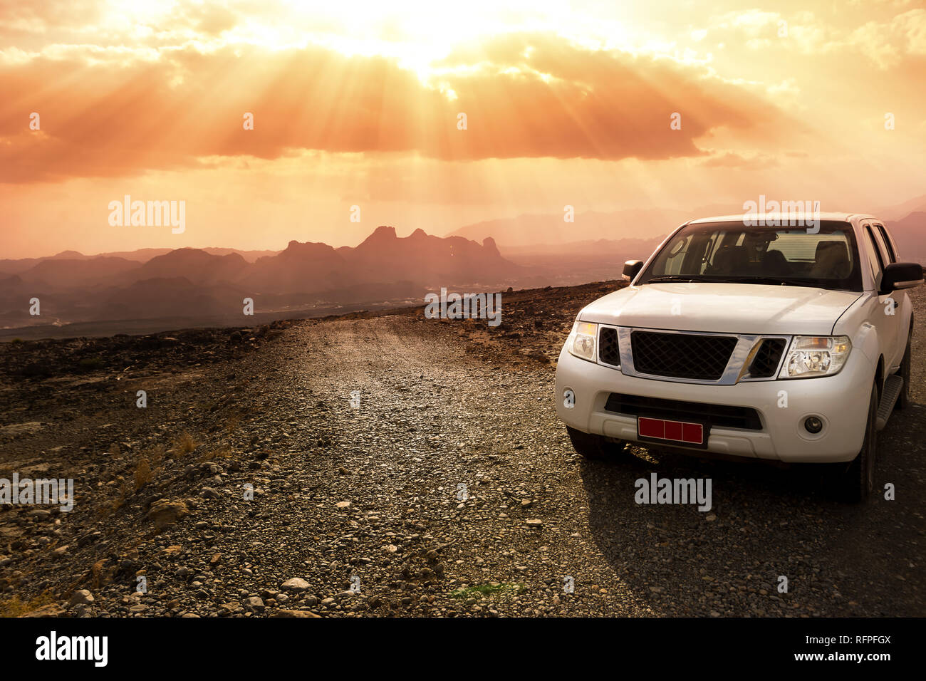 Veicolo fuoristrada sul Jebel Shams montagne e il cielo nuvoloso con raggi solari sorprendenti Foto Stock