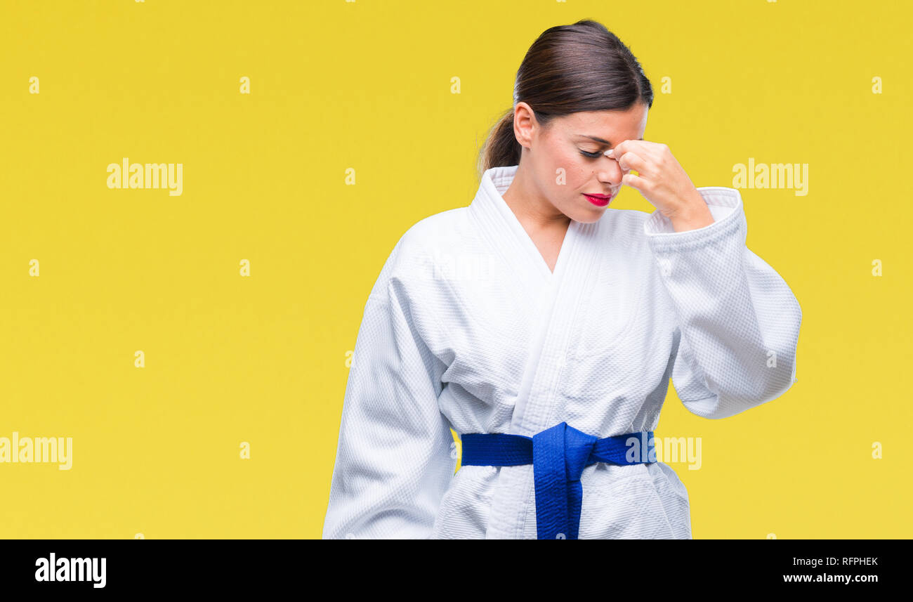 Giovane bella donna che indossa il karate kimono uniforme su sfondo isolato stanco strofinando il naso e gli occhi sensazione di stanchezza e mal di testa. Lo stress e le unità FRU Foto Stock