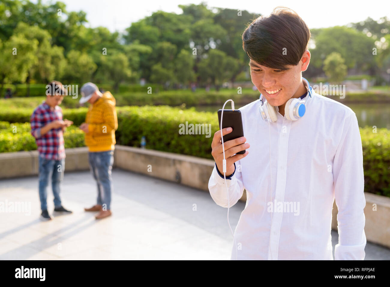 Tre giovani uomini asiatici di relax presso il parco insieme Foto Stock