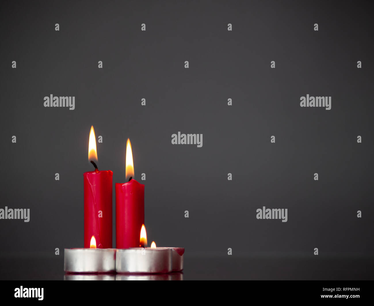 Concetto di amore candele rosse accese con sfondo grigio Foto Stock