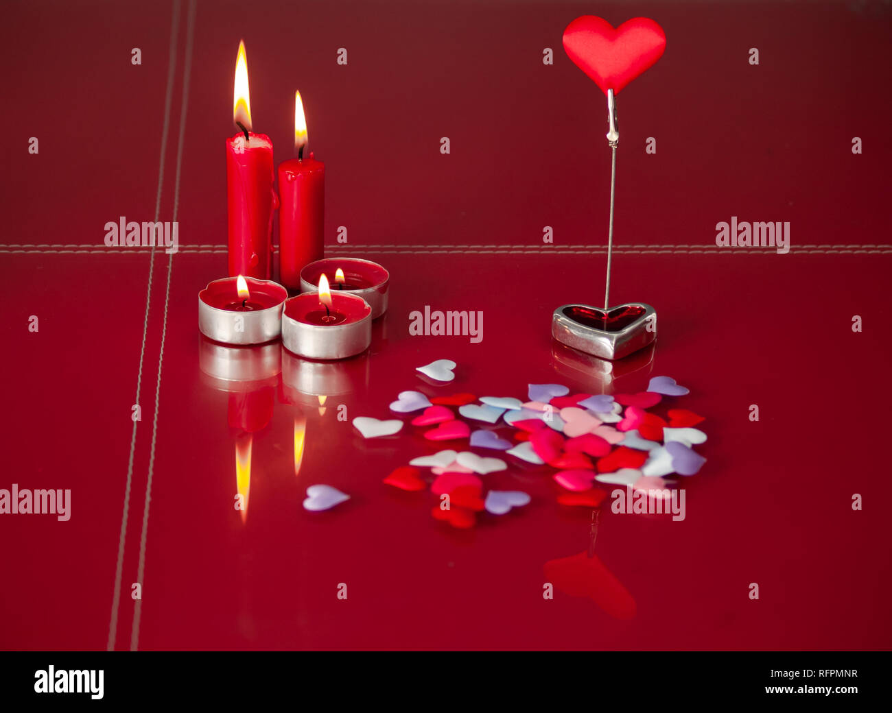 Concetto di amore candele rosse accese e un sacco di cuori con uno sfondo rosso Foto Stock