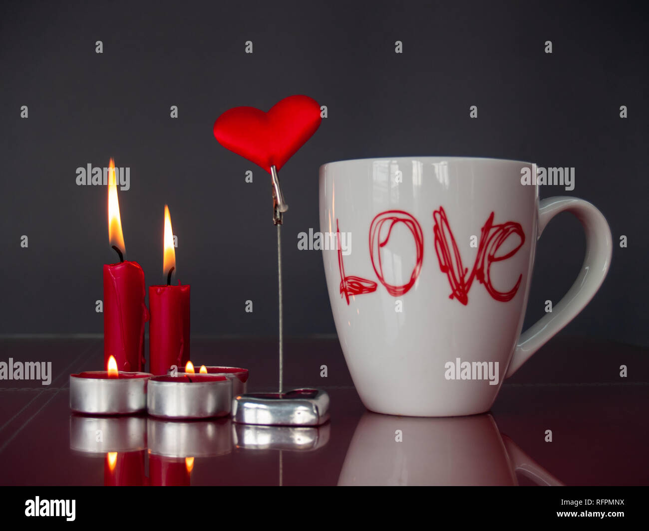 Concetto di amore ancora vita con rosso acceso candele, un cuore rosso e una colazione cup con la parola amore Foto Stock