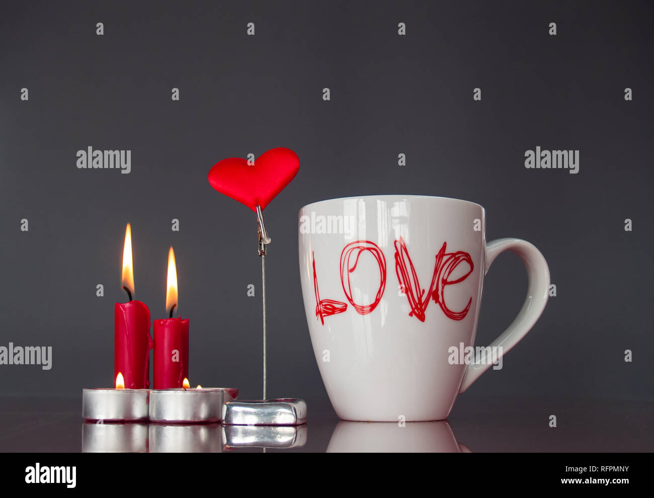 Concetto di amore ancora vita con rosso acceso candele, un cuore rosso e una colazione cup con la parola amore Foto Stock