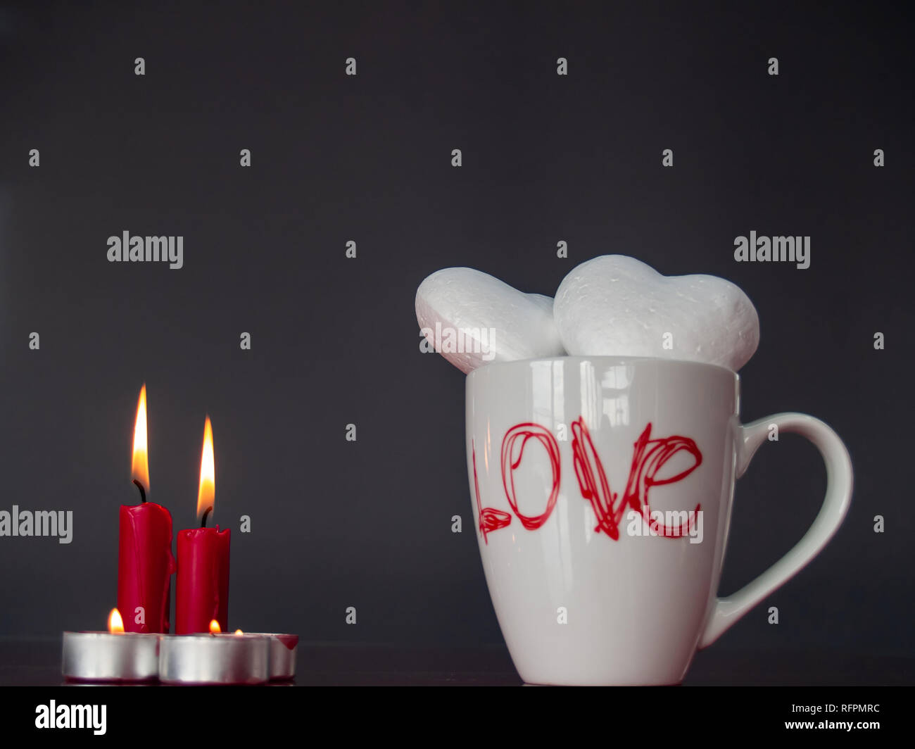 Concetto di amore ancora vita con rosso acceso candele e due cuori poliespan in una tazza colazione con la parola amore Foto Stock