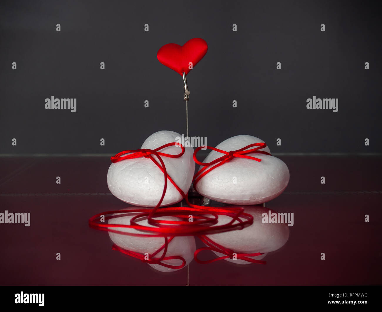 Concetto di amore poliespan due cuori uniti con un filo rosso che  simboleggia la leggenda del filo rosso e un cuore rosso Foto stock - Alamy