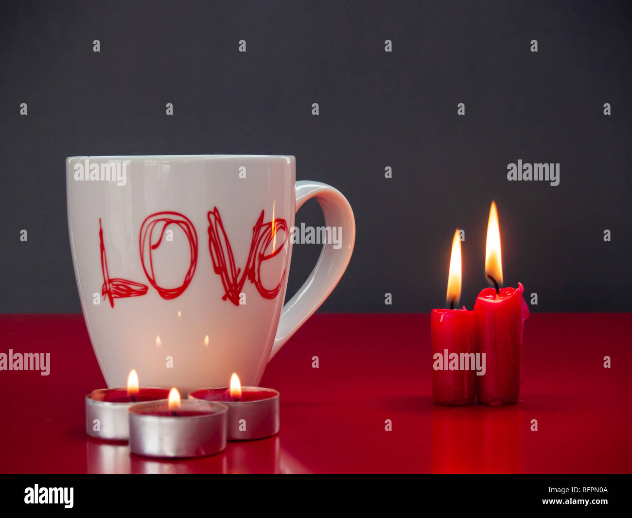 Concetto di amore ancora vita con rosso acceso candele e una colazione cup con la parola amore Foto Stock