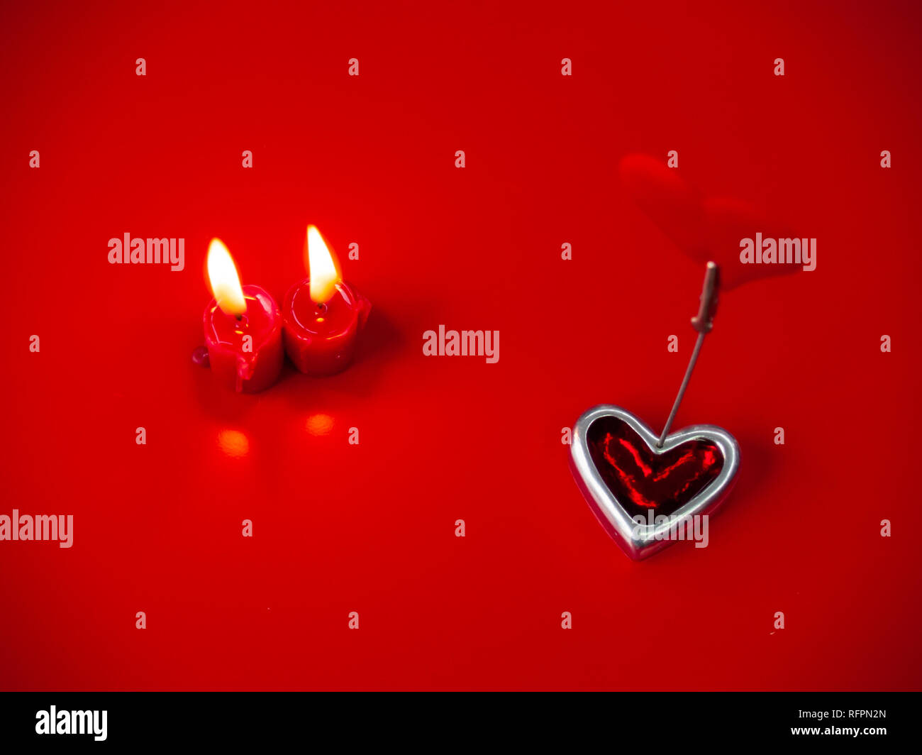 Concetto di amore candele rosse accese e cuore rosso con uno sfondo rosso Foto Stock