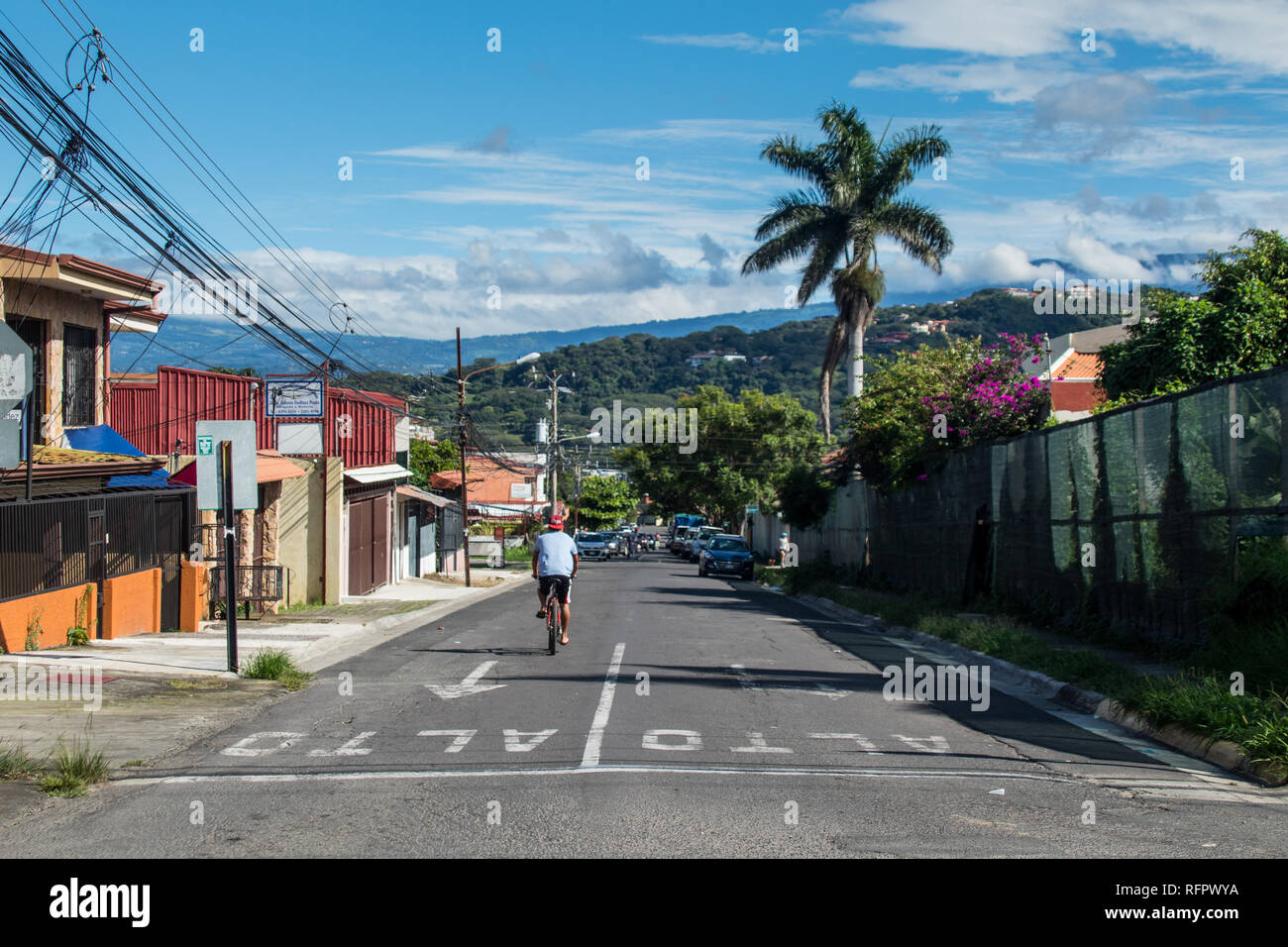 Una bella vista di una strada a Santa Ana. Un solitario biciclist riding sullo sfondo della Scenic paesaggio montuoso che circondano la valle centrale. Foto Stock