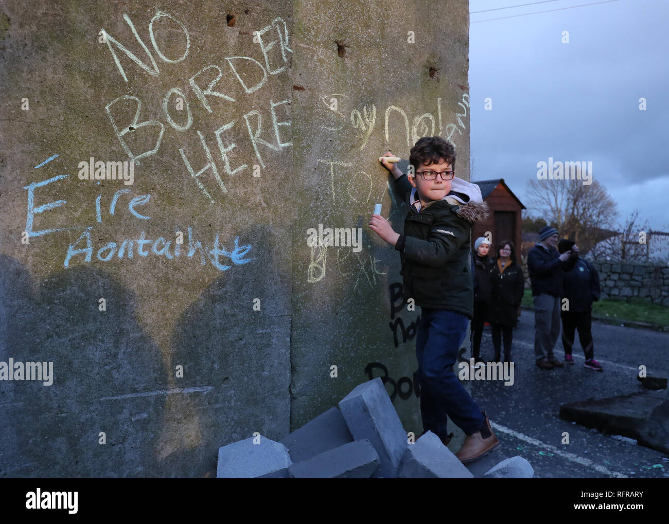 Un ragazzo scrive un messaggio su blocchi di cemento che sono stati temporaneamente installato come parte di un anti-Brexit al rally di frontiera irlandese vicino Carrickcarnan, Co Louth. Foto Stock