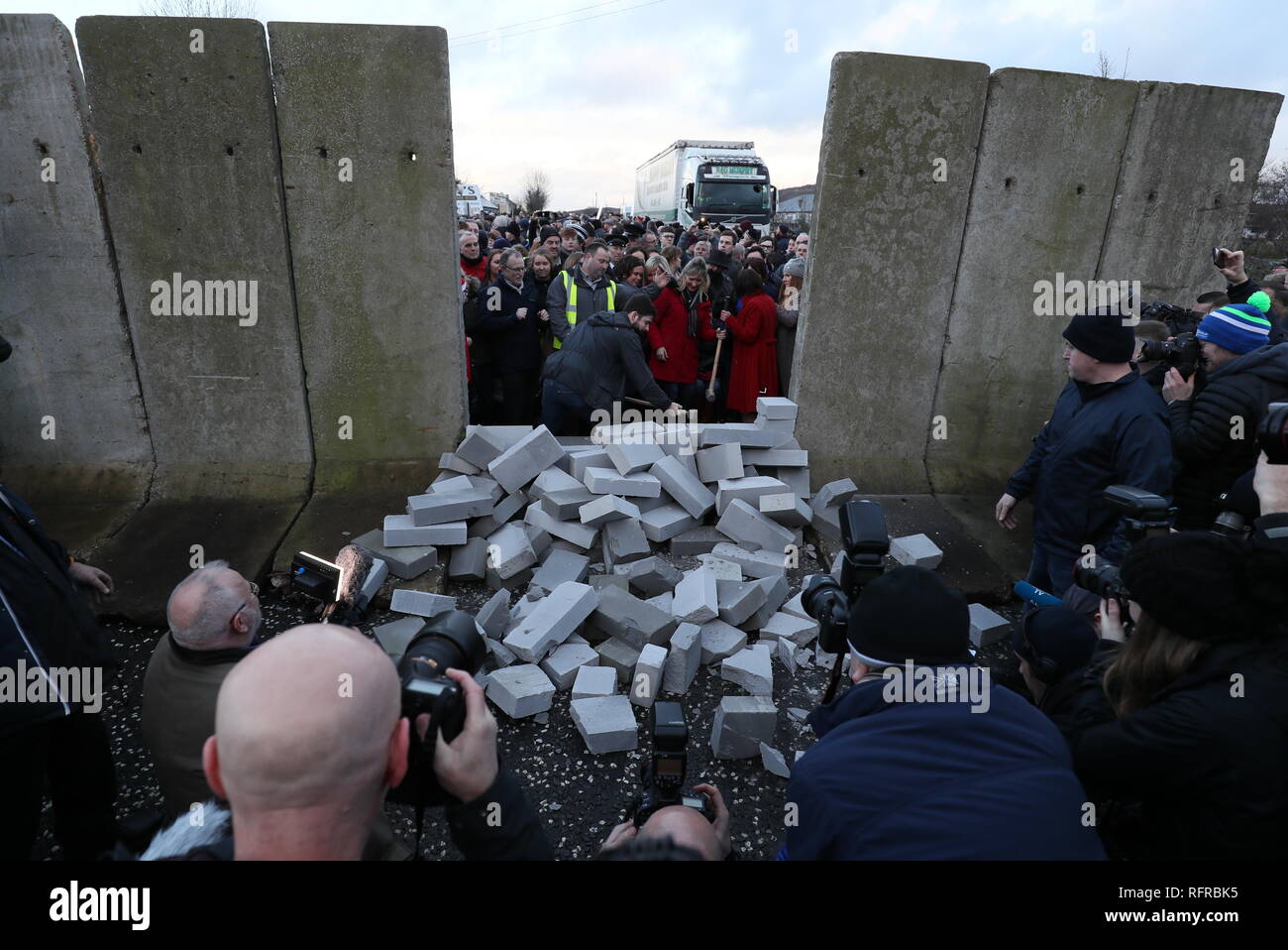 Manifestanti abbattere un muro simbolico che fu costruita come parte di un anti-Brexit al rally di frontiera irlandese vicino Carrickcarnan, Co Louth. Foto Stock