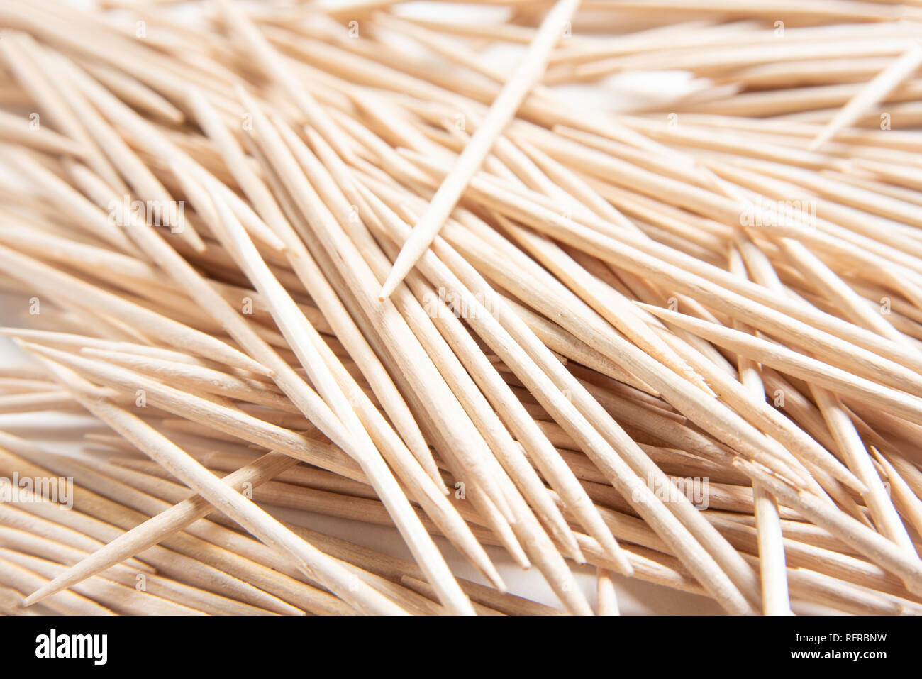 Un mazzetto di inutilizzati round stuzzicadenti di legno abilmente sparsi su un semplice sfondo bianco. Foto Stock