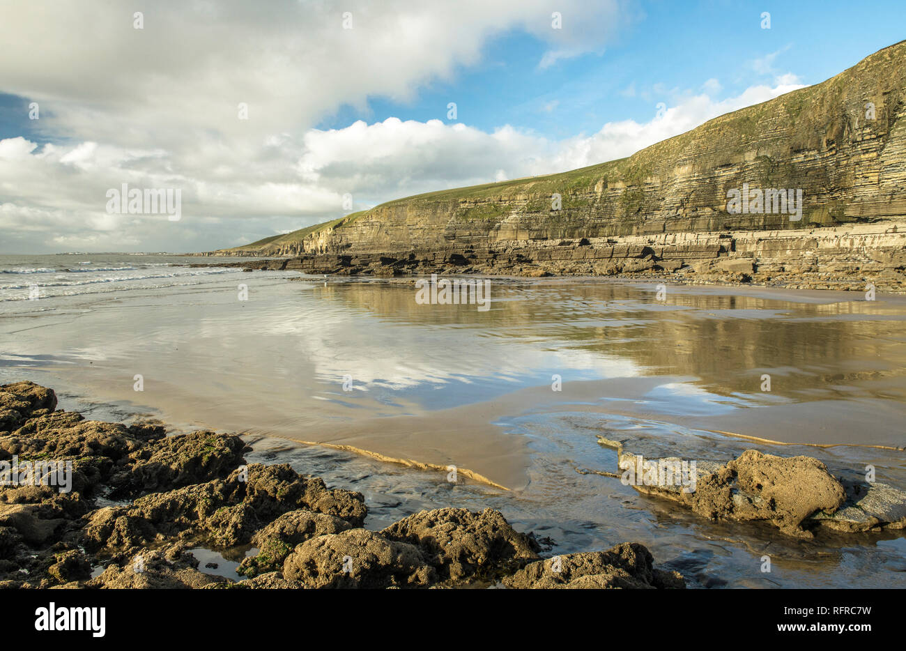 Dunraven Bay, Southerndown, in Glamorgan Heritage Coast. Il sole invernale provoca riflessioni cloud nella sabbia bagnata Foto Stock