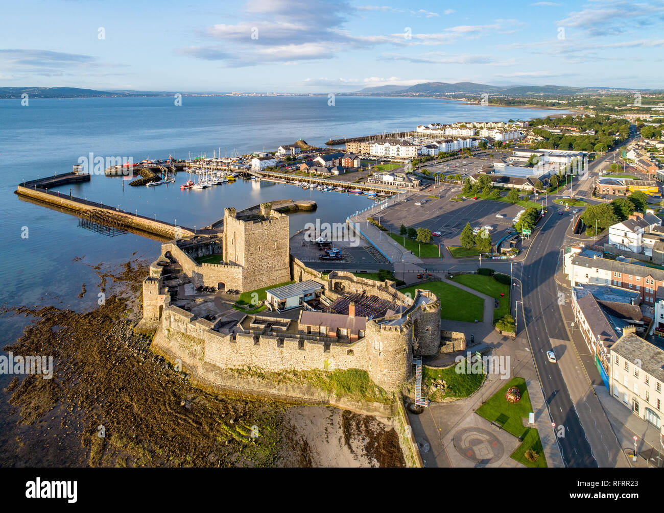 Belfast Lough. Medievale Castello normanno a Carrickfergus nella luce di sunrise. Vista aerea con marina, yacht, parcheggio, frangiflutti e sedimenti. Foto Stock