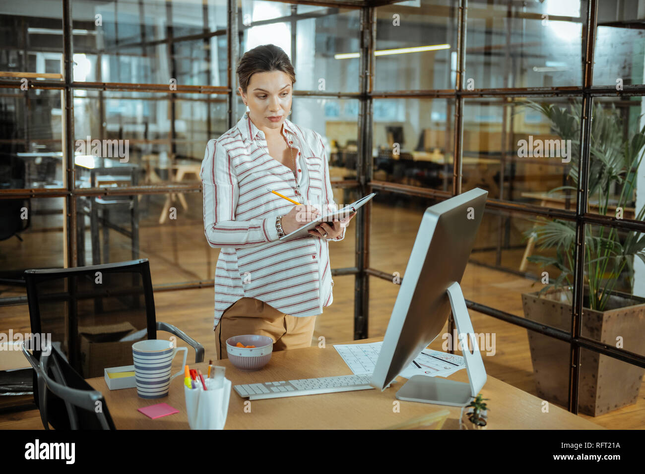 Imprenditrice incinta mentre tiene il suo notebook mentre facendo alcune note Foto Stock