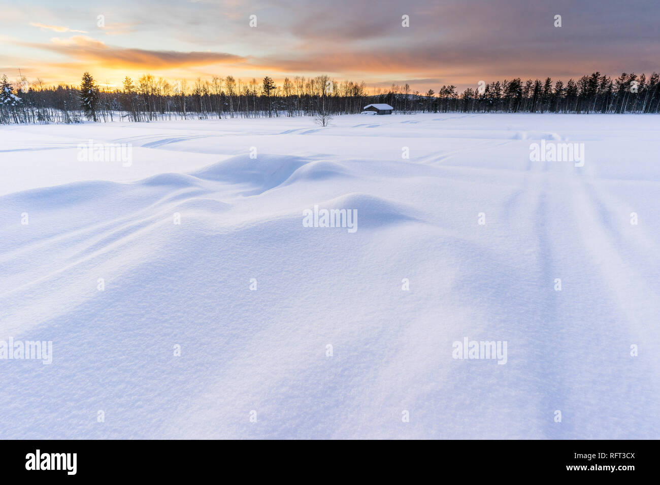 Tramonto in inverno in Lapponia finlandese con log cabin e foresta in background, neve profonda in primo piano. La foto è stata scattata in Pyha, Finlandia. Foto Stock