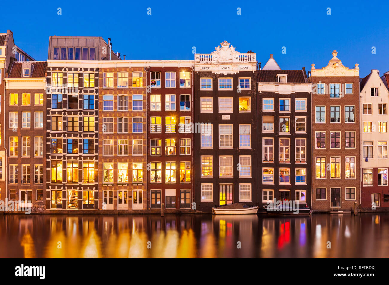 Dutch gables sulla fila di tipiche case di Amsterdam di notte con riflessioni a Damrak canal, Amsterdam, Olanda Settentrionale, Paesi Bassi, Europa Foto Stock