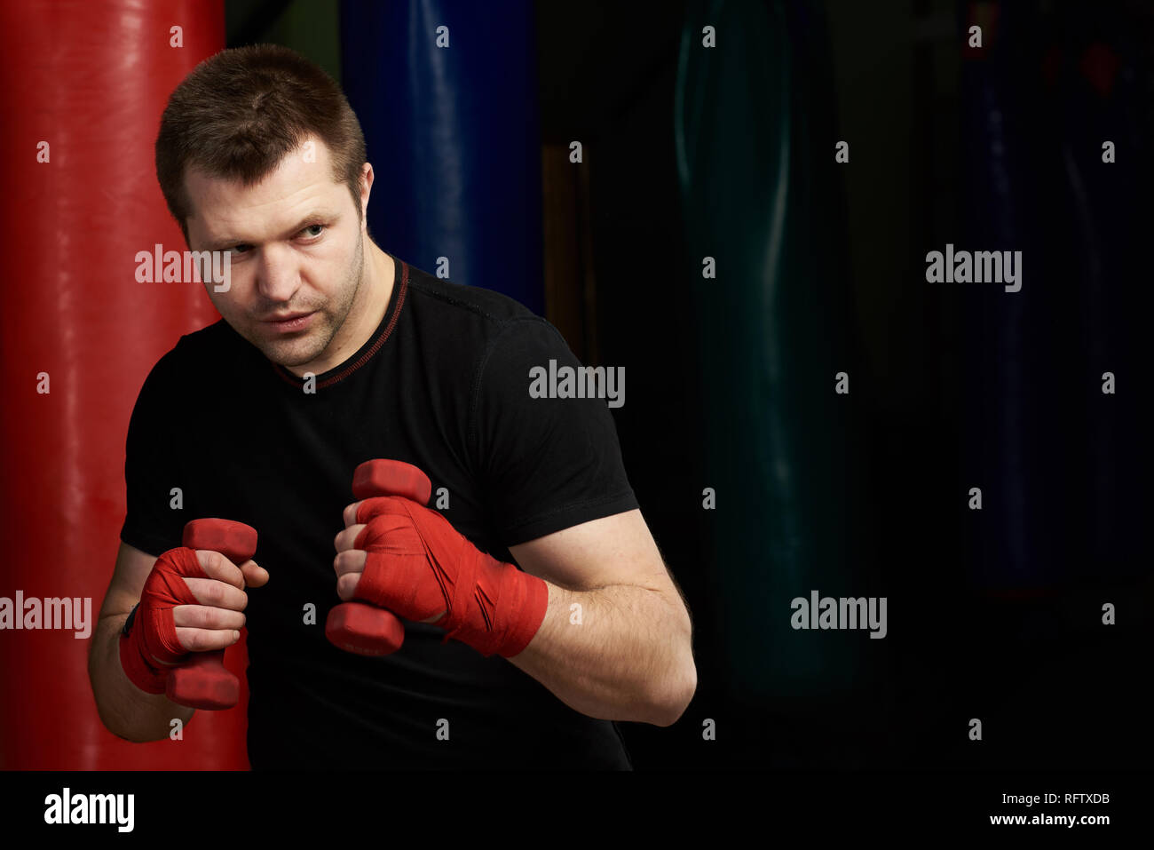 Un boxer esercizio punzone con pesi su una palestra moderna sullo sfondo Foto Stock