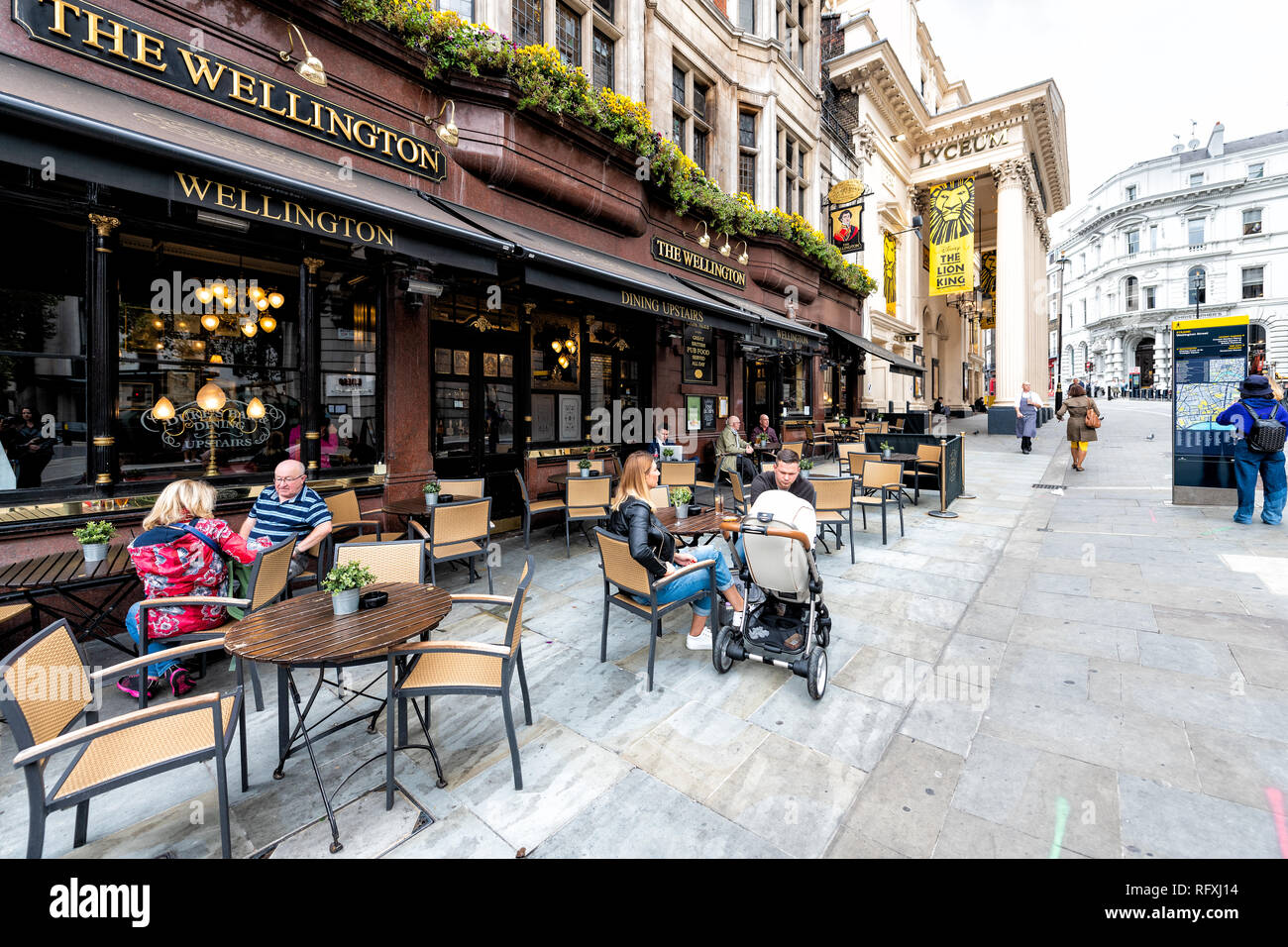 London, Regno Unito - 12 Settembre 2018: la gente seduta sulla strada per strada con il Wellington pub ristorante segno e marciapiede in The Strand in Covent Garden Foto Stock