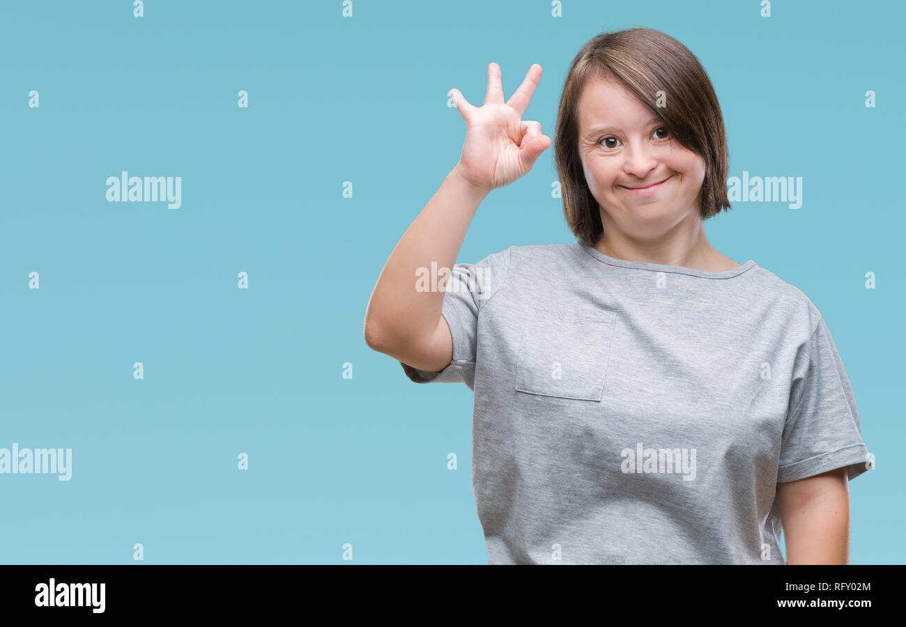 Giovane donna adulta con la sindrome di down su sfondo isolata positiva sorridente facendo segno OK con la mano e le dita. Espressione di successo. Foto Stock