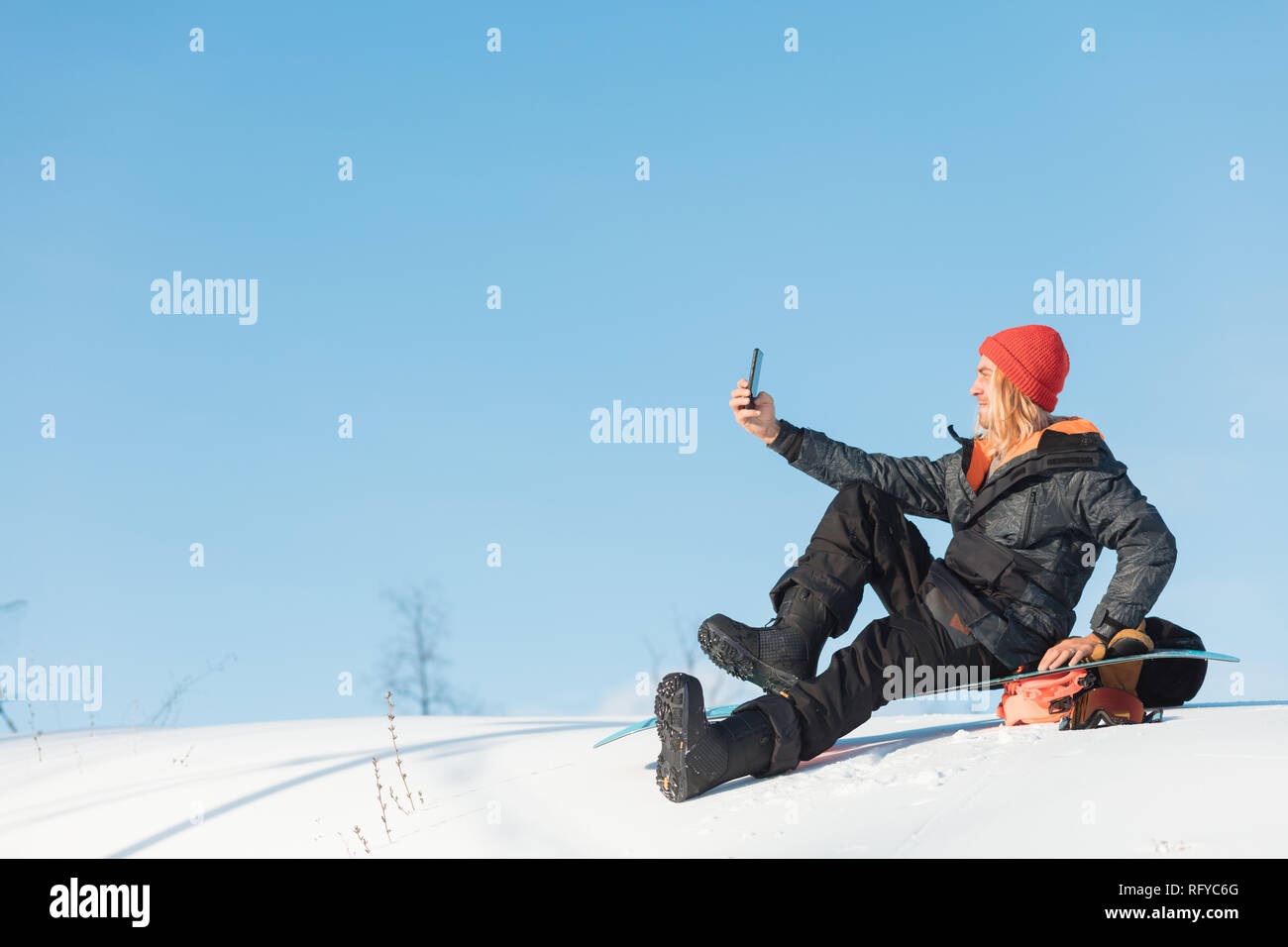 Allegro bionda uomo in inverno Abbigliamento snowboard seduta Foto stock -  Alamy