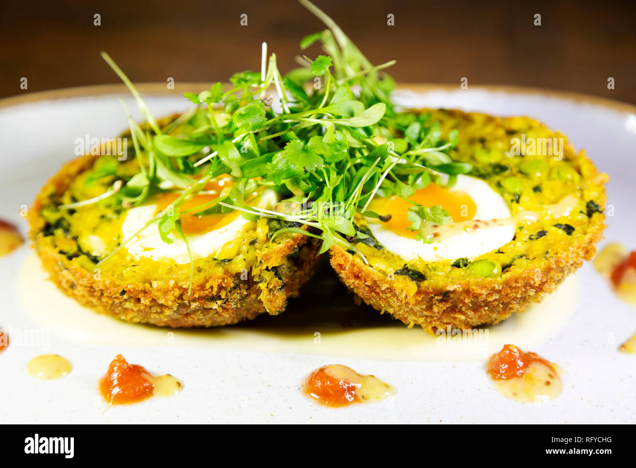 Kedgeree Scotch uovo guarnita con insalata verde. L'uovo è un soft-cotto a metà e viene servito con un chutney guarnire. Foto Stock