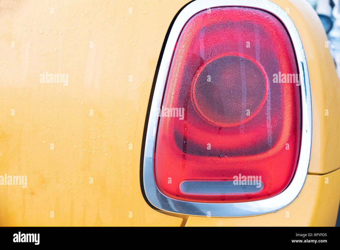 Gocce di acqua su Mini Cooper's luce posteriore / luce di stop con copia gialla spazio Foto Stock