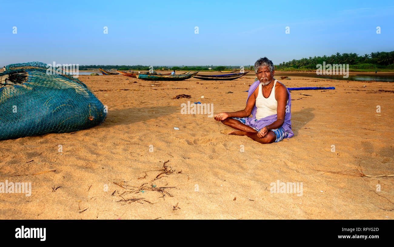 Un anziano pescatore seduto sulla spiaggia, spazio di copia Foto Stock