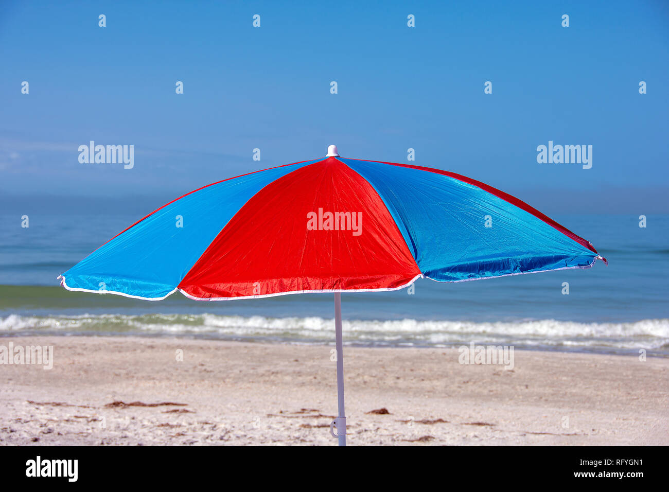 Rosso e blu luminoso ombrellone sulla spiaggia in Florida con Sfondo oceano Foto Stock