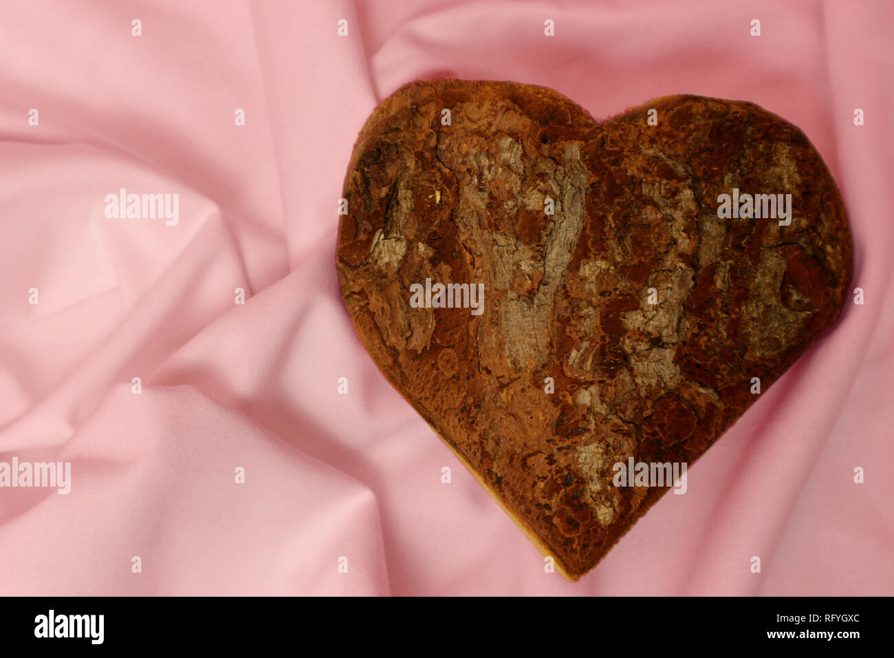 Cuore di legno sul velluto rosa coperta Foto Stock