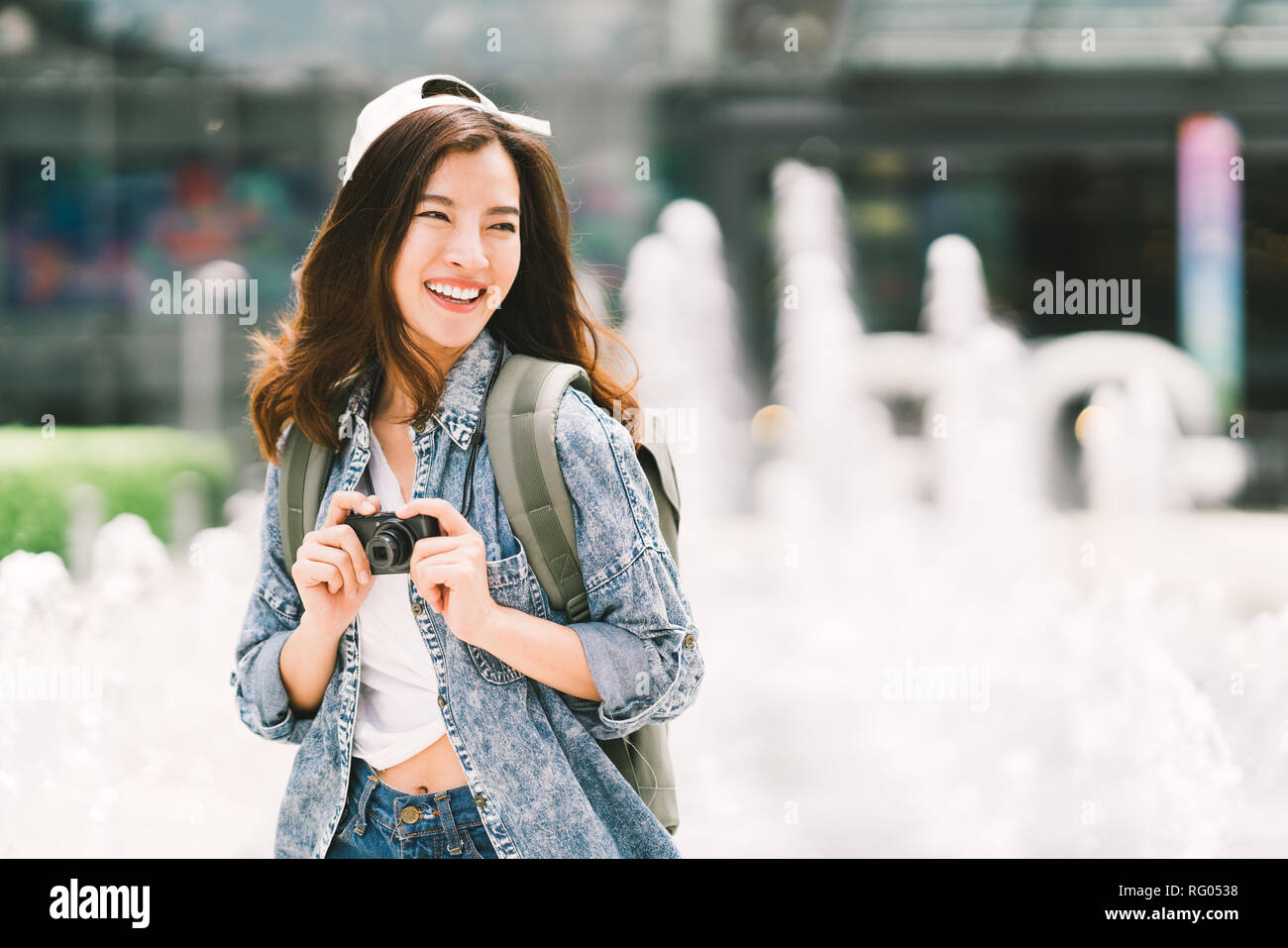 Giovane bella asiatica viaggiatore zainetto donna usando fotocamera digitale compatta e sorriso, cercando di copiare lo spazio. Viaggio viaggio lifestyle, world travel Foto Stock