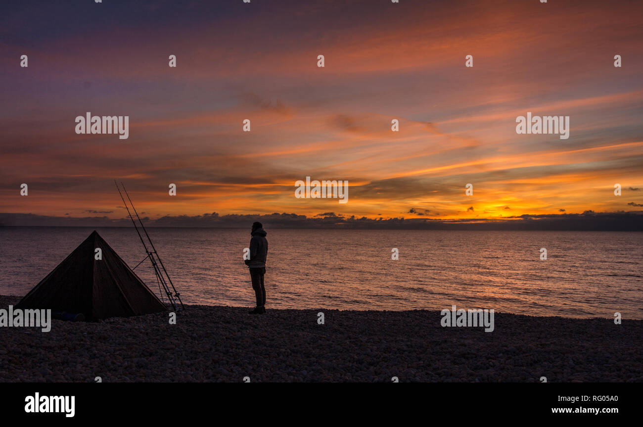 Fisherman/pescatore di mare durante il tramonto a Ferrybridge, Chesil, Dorset, Regno Unito Foto Stock