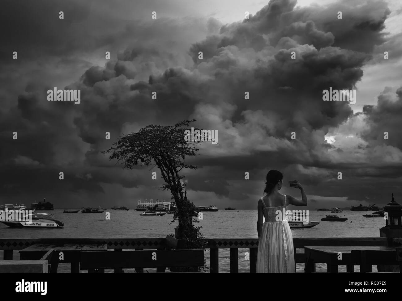 Una donna asiatica è la realizzazione di una immagine dal NUVOLOSO TRAMONTO Foto Stock