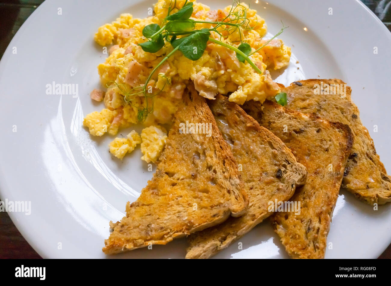 La colazione brunch o inizio pranzo in una caffetteria uova strapazzate con salmone affumicato e multi grano pane tostato e crescione guarnire Foto Stock